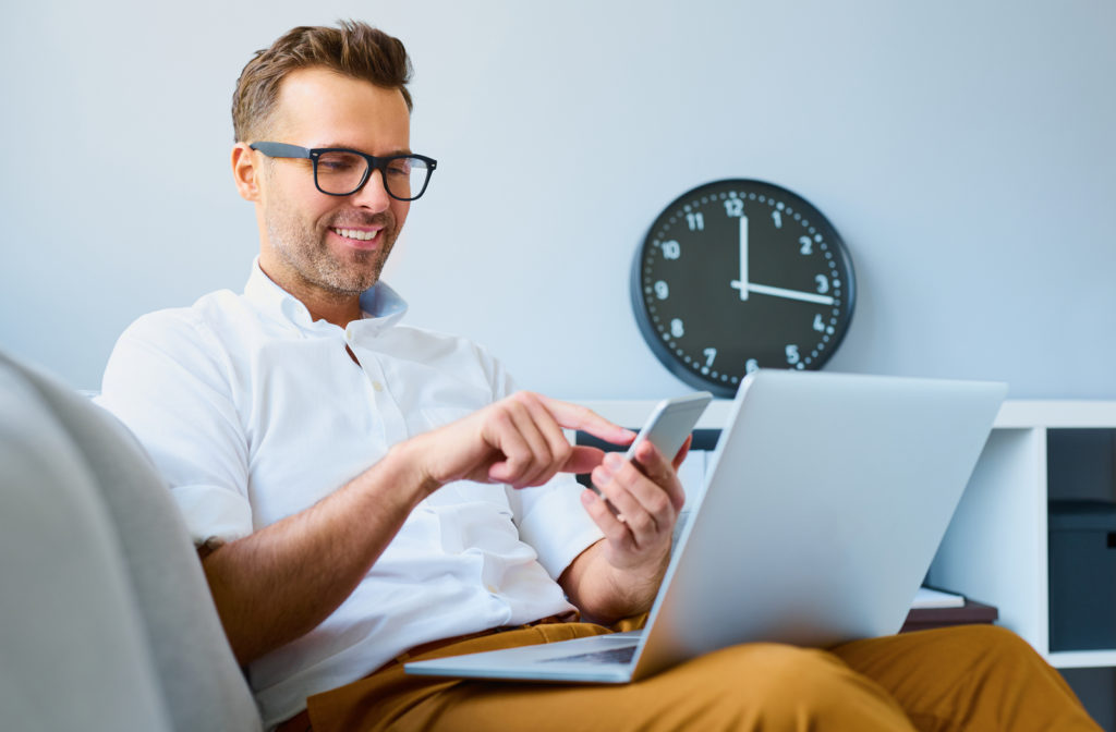 Man preventing digital eyestrain while using a phone and laptop.