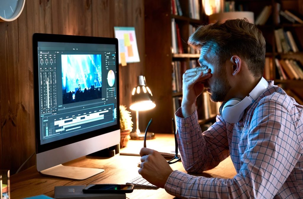 Young man frustrated due to dry eyes due to the glare from his computer.