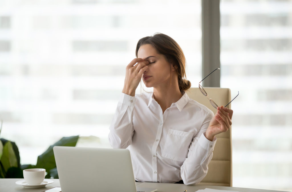 Woman frustrated due to dry eye while working on laptop