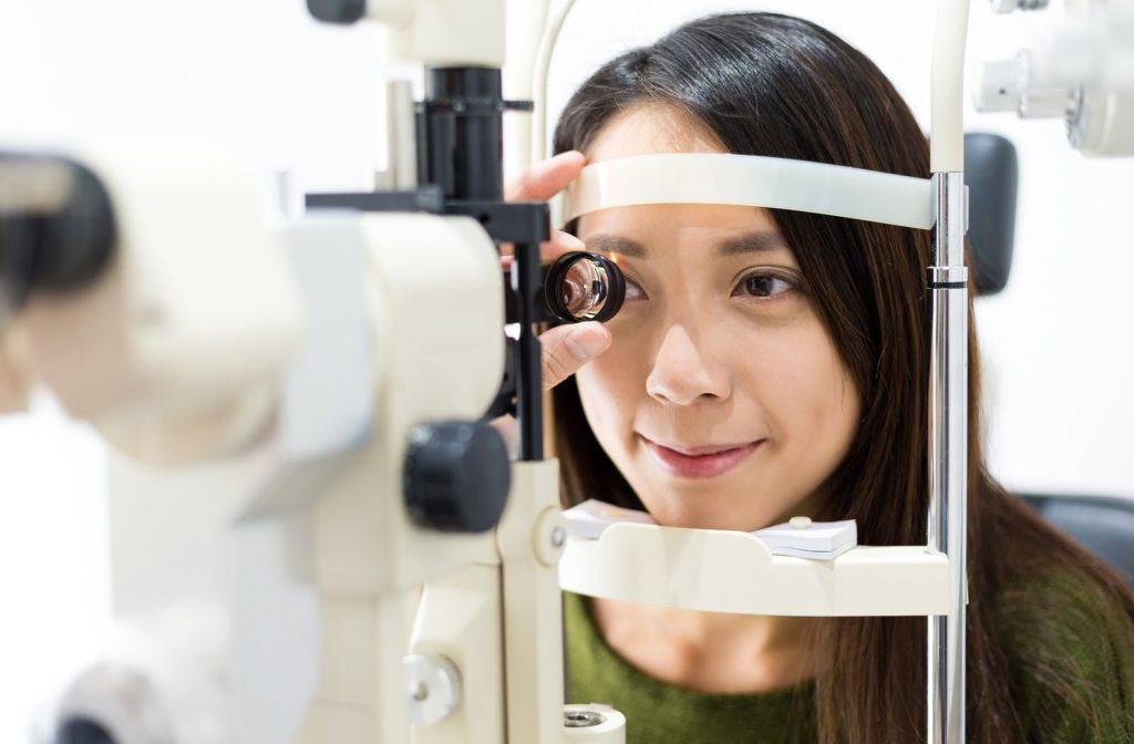 Happy young woman undergoing visual field test by her optometrist