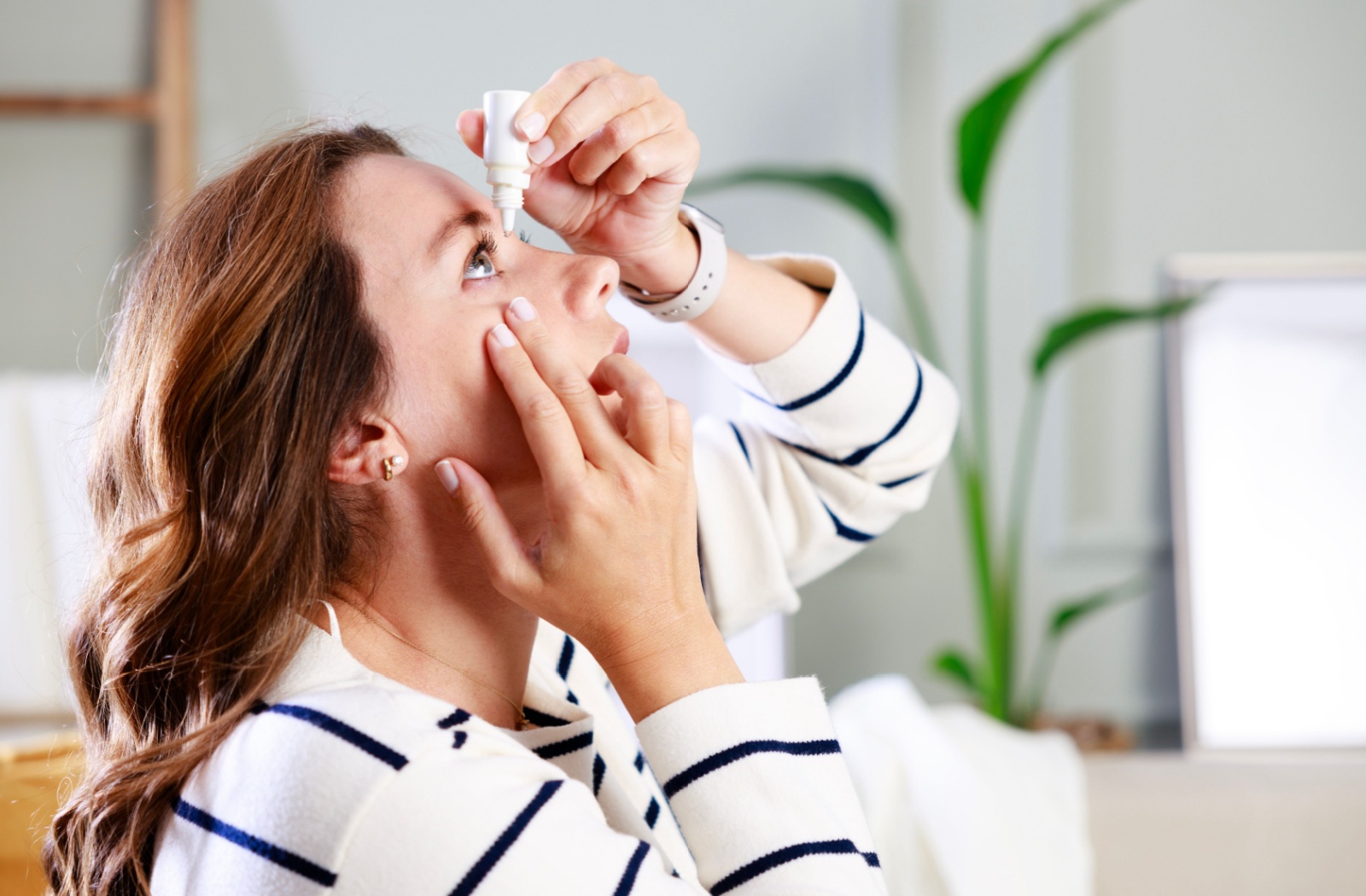 A person applies eye drops to soothe their dry eye symptoms.
